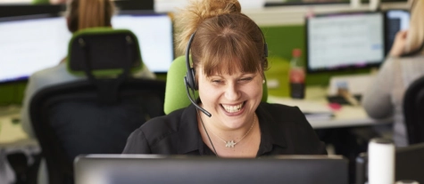 Smiling woman in a call center answers the phone with a hands-free headset 